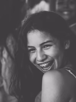 Black and white portrait of a young woman with braces, laughing