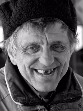 Black and white portrait of an older man in a knit hat, smiling