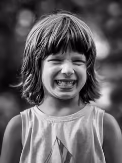 Black and white portrait of a child grinning with a gap-toothed smile